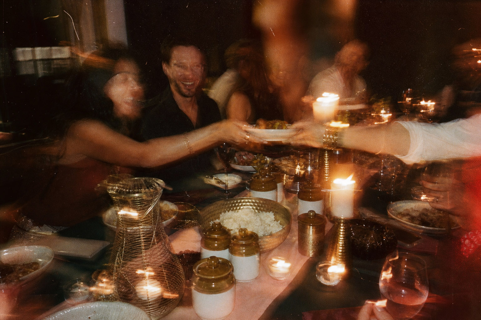 Guests sharing food around a warm candlelit table